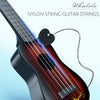 A close-up of a dark wood ukulele showing nylon string guitar strings and a pick.