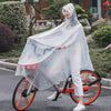A woman wearing a transparent waterproof motorcycle rain poncho is riding an orange bicycle outdoors.