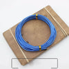 Blue anodized aluminum jewelry wire coiled on a wooden board with thin twine.