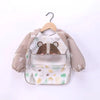 A beige and brown striped long-sleeve baby feeding smock with a bear face design, hanging on a wooden hanger.
