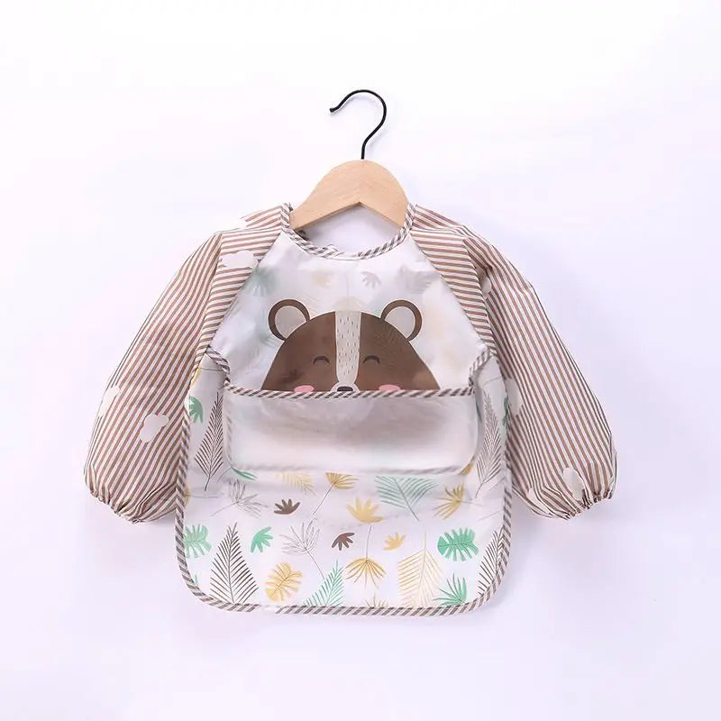 A beige and brown striped long-sleeve baby feeding smock with a bear face design, hanging on a wooden hanger.