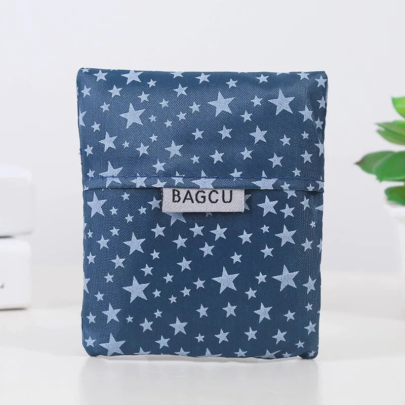 A dark blue fabric shopping bag patterned with small stars and featuring a rectangular tag that reads BAGCU.
