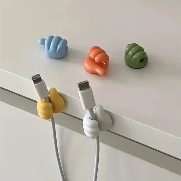 Un juego de clips organizadores de cables adhesivos coloridos en azul, naranja y verde montados en una superficie blanca.