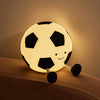 A glowing soccer ball night light with black and white panels rests on a beige surface.