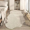 A light beige irregular area rug with a plush texture placed on a wooden floor next to a white sofa and sheer curtains.