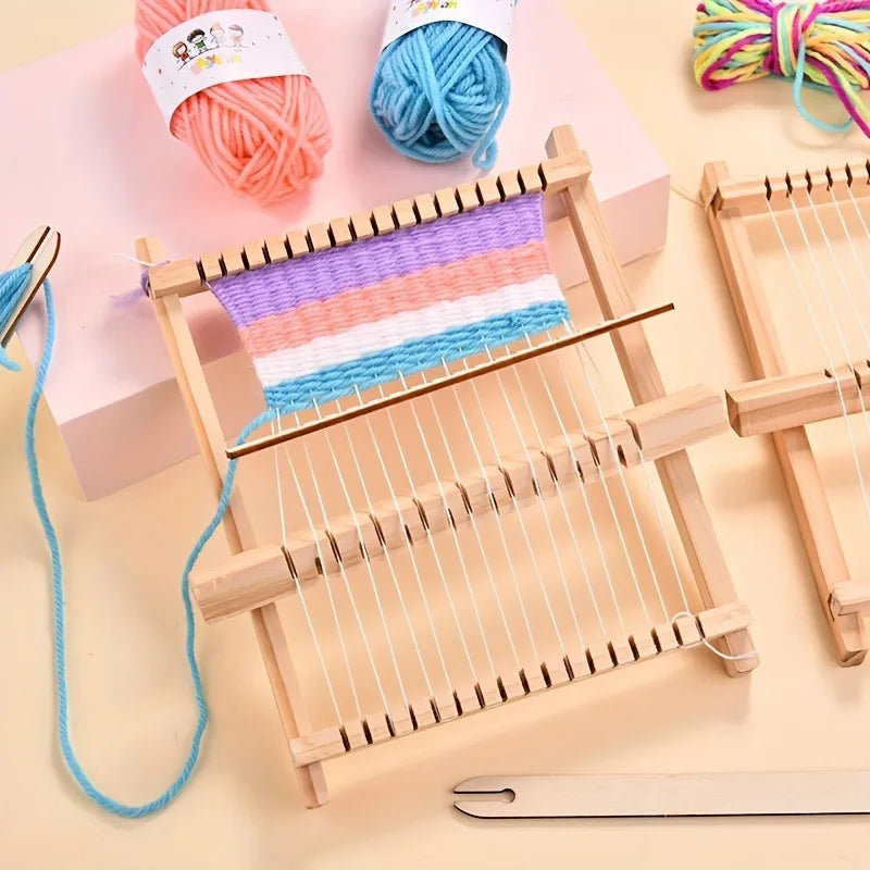 A wooden weaving loom kit with colorful yarn and threads is displayed on a light pink background.