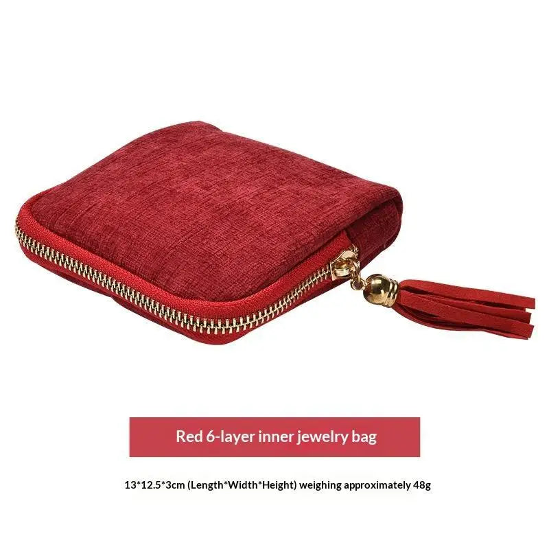 A deep red velvet jewelry organizer pouch with a zipper closure.