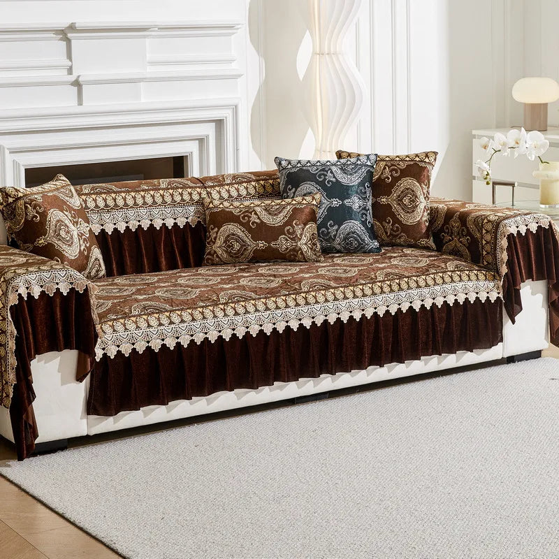 A brown and gold patterned sofa cover with decorative trim and accent pillows displayed on a white sofa.