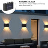 A solar powered outdoor wall light with up and down illumination mounted on a white exterior wall.