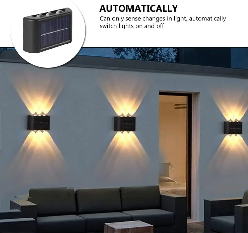 A solar powered outdoor wall light with up and down illumination mounted on a white exterior wall.
