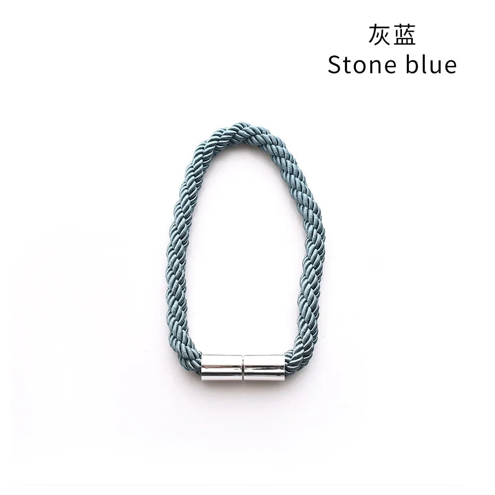 A close-up of a stone blue rope tieback with a silver magnetic clasp.