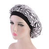 A woman wearing a black satin hair bonnet with a zebra print fabric on a mannequin head.