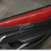 Close-up view of a red interior and exterior trim kit installed on a black car door panel.