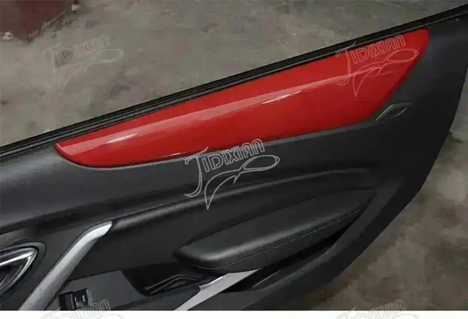Close-up view of a red interior and exterior trim kit installed on a black car door panel.