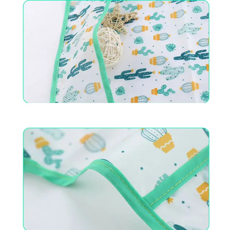 A white waterproof long sleeve art smock and feeding bib with a light green trim featuring colorful cactus patterns.