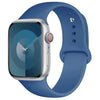 A silver Apple Watch encased in a blue silicone sport band.