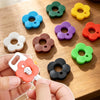 A hand holds a silicone flower key cover in various colors, demonstrating colorful protectors for easy key identification.