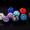 A collection of colorful crystal clay round beads in various shades including blue, purple, pink, and red, displayed on a dar