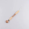A string of wooden beads and fabric flowers with the name BABY and a silicone clip on a white background.