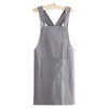 A gray linen kitchen apron hanging on a wooden hanger.