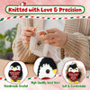 Hands knitting a white penguin doll using yarn and needles with a green and red striped background.