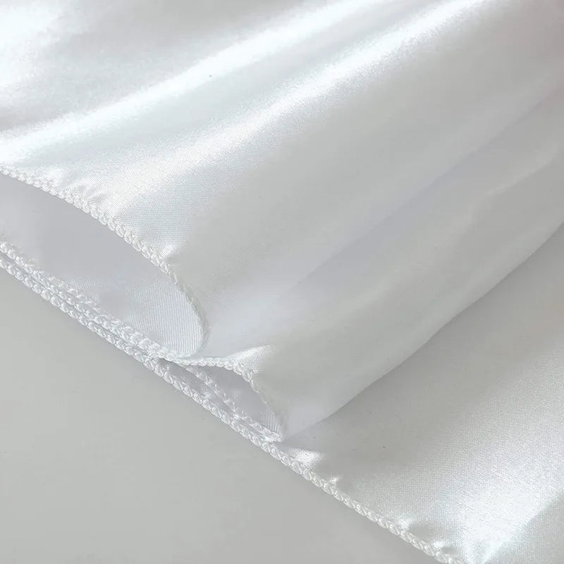 A close-up of an elegant white satin table runner fabric folded and draped.