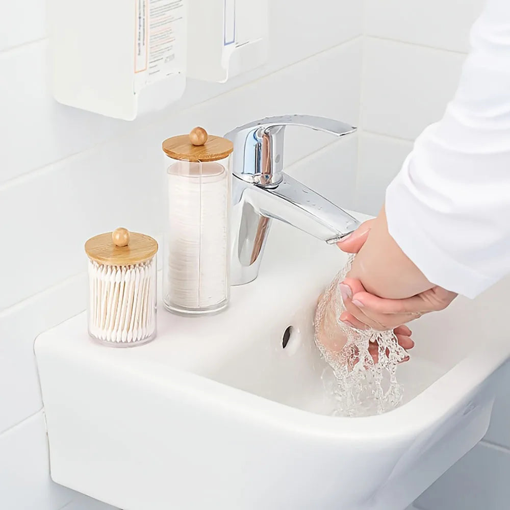 A set of three cotton swabs and a bathroom organizer are shown next to a chrome faucet in a white sink.