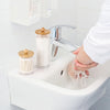 A set of three cotton swabs and a bathroom organizer are shown next to a chrome faucet in a white sink.