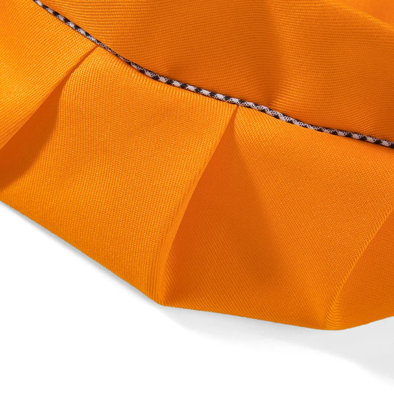 Orange fabric of a kids' craft apron and chef hat set with a black striped detail.