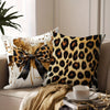 A decorative pillow featuring a leopard print design with an orange and black bow on a light background.