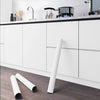 A roll of white self-adhesive peel-and-stick wallpaper lying on a dark wooden floor.