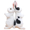 A pair of white and black lifelike plush rabbit stuffed animals standing side by side.