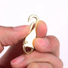 A gold-colored metal zipper slider is held between fingers against a white background.