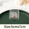 A clear self-sealing jewelry storage bag containing pearl and gold-toned earrings, displayed on a dark green plate.