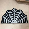 Black and white decorative rug shaped like a spider web with a ghost design