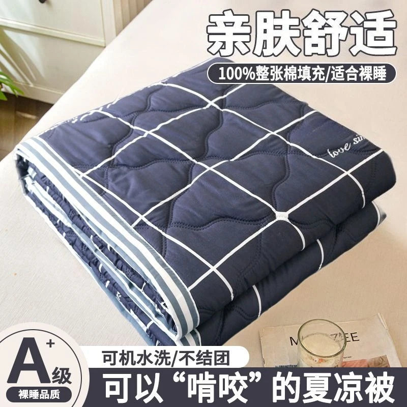 A folded navy blue quilted blanket with white stitching and a label indicating it is suitable for summer.