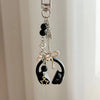 Silver metal music note charm with black beads and a bow detail