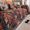 A richly colored floral jacquard sofa blanket with tassels draped over a sofa.