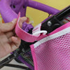 A hand is adjusting the pink mesh organizer on a purple stroller frame.