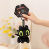 A hand is holding a black plush dragon toy with green eyes and a tag that reads Dragons