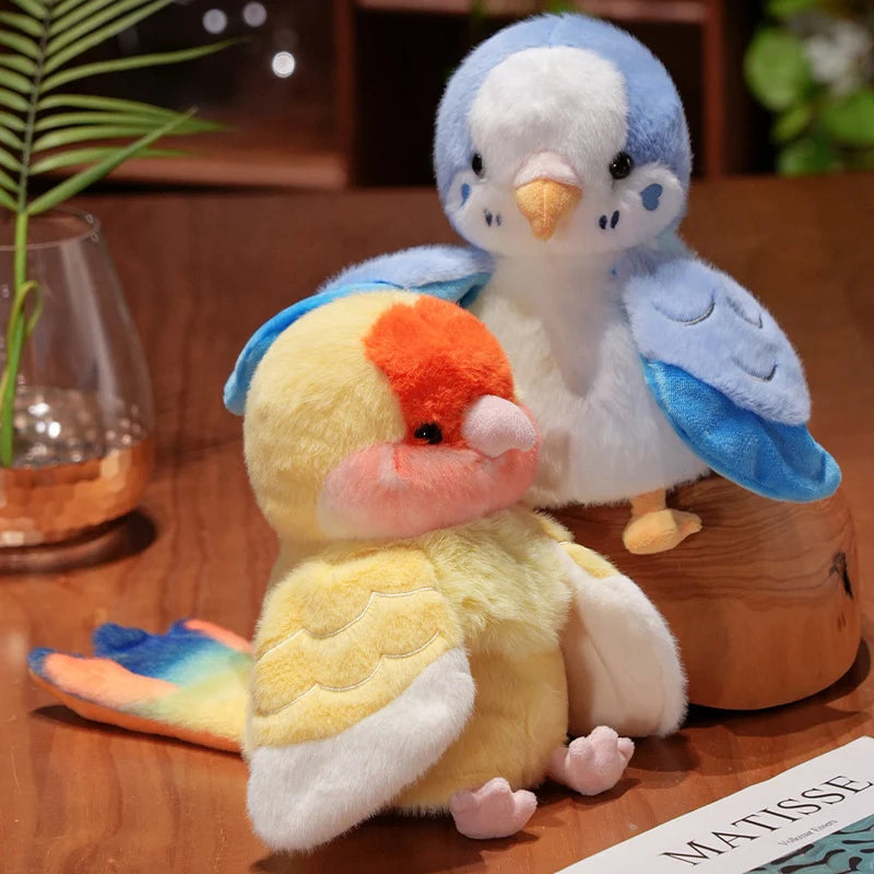 A fluffy blue and white plush parrot toy with an orange beak sits next to a yellow and white plush bird.