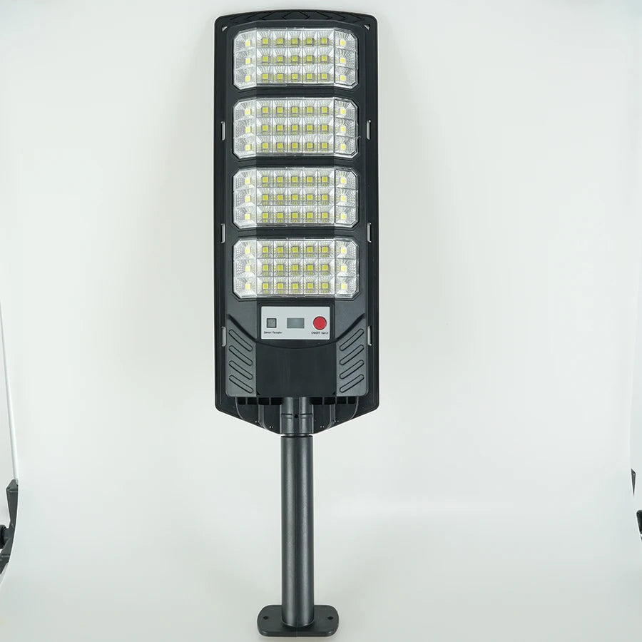 A black solar wall light fixture with multiple LED panels and a motion sensor mounted on a metal pole.