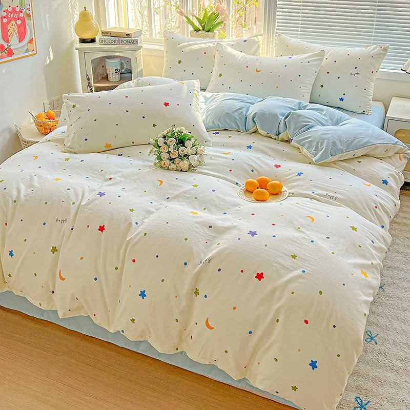 A white floral duvet cover set with a blue accent, featuring a flat sheet and pillows on a bed.