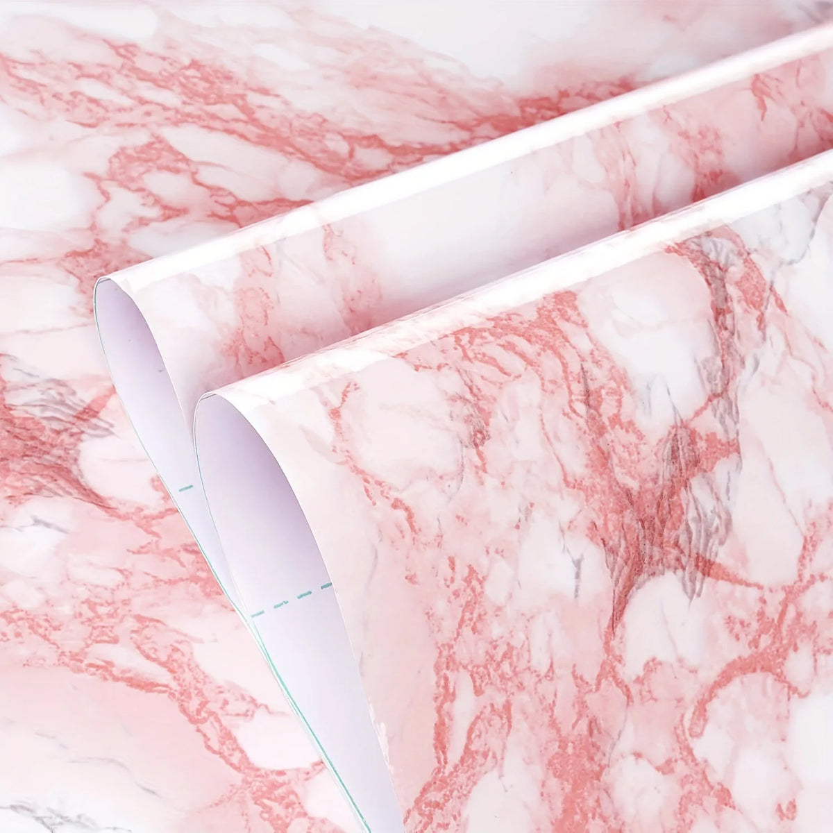 Rolls of pink and white marble wallpaper showing the natural veining pattern.
