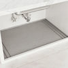 A silicone under sink cabinet protector mat is placed inside a white kitchen cabinet.