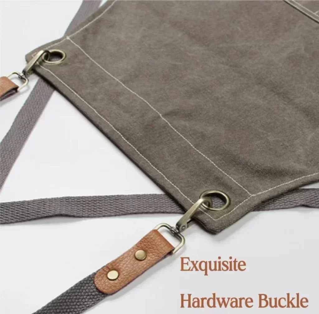 A gray cotton canvas apron featuring hardware buckles and cross-back straps.