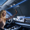 A woman in a car interior adjusts a foldable car windshield sunshade with a storage pouch.