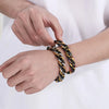 A hand is putting on a chunky stainless steel Cuban chain bracelet for men.