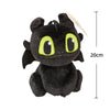 A black soft plush dragon toy resembling a Night Fury with bright yellow eyes and a small feather.