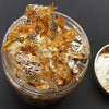 A clear jar filled with gold metallic foil flakes for crafting projects.